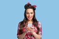 Beautiful pinup woman in retro outfit using smartphone, browsing internet, checking email or chatting in social networks