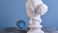 Beautiful plaster Aphrodite looks at herself in a small mirror with a mystical soft blue light.