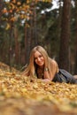 Beautiful playful girl relaxing on yellow leaves