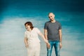 Beautiful plump woman holds the hand of a tall bald man on a blue background. Royalty Free Stock Photo