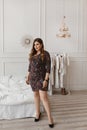 Beautiful plus size model girl in a modish dress looking in camera in a bedroom interior. Young plump woman with bright Royalty Free Stock Photo