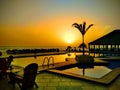 Beautiful poolside and sunset sky in Senegal, Africa. Luxurious tropical beach landscape with palms, deck chairs and loungers.. It Royalty Free Stock Photo