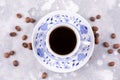 A beautiful porcelain coffee cup with hot black coffee. Coffee beans scattered around the background. Vintage china. A white-blue Royalty Free Stock Photo