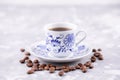 A beautiful porcelain coffee cup with hot black coffee. Coffee beans scattered around the background. Vintage china. A white-blue Royalty Free Stock Photo