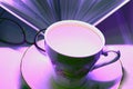 Beautiful porcelain Cup on a saucer with a book and reading glasses