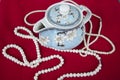 Beautiful porcelain teapot and pearl necklaces on red floor