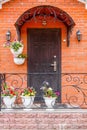 A beautiful porch in a rich house with black door, red brick wall and white flower pots. Royalty Free Stock Photo