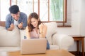 Beautiful portrait asian young couple working laptop with smile and happy sitting on couch at living room Royalty Free Stock Photo