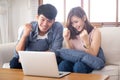 Beautiful portrait asian young couple working laptop with smile and happy sitting on couch at living room Royalty Free Stock Photo