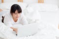 Beautiful portrait asian young woman smile lying on bed using laptop computer with happy at bedroom for leisure and relax Royalty Free Stock Photo