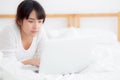 Beautiful portrait asian young woman smile lying on bed using laptop computer with happy at bedroom for leisure and relax Royalty Free Stock Photo
