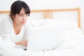 Beautiful portrait asian young woman smile lying on bed using laptop computer with happy at bedroom for leisure and relax Royalty Free Stock Photo