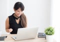 Beautiful portrait asian young woman smile working online laptop computer with happy satisfied sitting on desk office Royalty Free Stock Photo