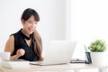 Beautiful portrait asian young woman smile working online laptop computer with happy satisfied sitting on desk office Royalty Free Stock Photo