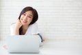 Beautiful of portrait asian young woman working online laptop lying on floor brick cement background Royalty Free Stock Photo