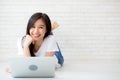 Beautiful of portrait asian young woman working online laptop lying on floor brick cement background