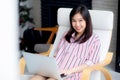 Beautiful of portrait asian young woman working online laptop with smile and happy sitting on chair Royalty Free Stock Photo