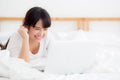 Beautiful portrait freelance asian young woman lying relax and leisure working laptop computer internet online on bed in bedroom