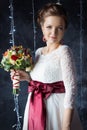 Beautiful portrait of a gentle cute happy bride in a white dress with a bright little colored bouquet