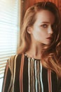 Beautiful portrait of a girl in profile. Girl stand near the window with blinds. Beautiful portrait of a girl. Photos with fashion
