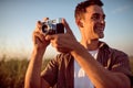 Beautiful portrait of handsome smile young man with vintage camera,on a meadow background. Travel mood. Photography.