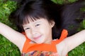 Beautiful portrait little girl asian of a smiling lying on green grass at the park. Royalty Free Stock Photo