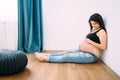 Beautiful portrait of pregnant woman sitting on hardwood floor and smiling to baby tummy Royalty Free Stock Photo