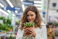 beautiful portrait of woman holding pot with home plant near face in flower shop Royalty Free Stock Photo