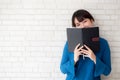 Beautiful portrait young asian woman happy hiding behind covering the book with cement or brick concrete background Royalty Free Stock Photo