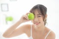 Beautiful portrait young asian woman holding and eating green apple fruit in the bedroom at home. Royalty Free Stock Photo