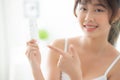 Beautiful portrait young asian woman holding and pointing presenting cream or lotion product Royalty Free Stock Photo