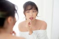 Beautiful portrait young asian woman looking mirror applying makeup lipstick at room Royalty Free Stock Photo