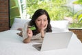 Beautiful portrait young asian woman lying users credit card with laptop Royalty Free Stock Photo