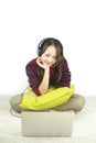 Beautiful portrait young asian woman sit on the floor with laptop and headphone on white background.