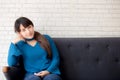 Beautiful portrait young asian woman sitting and smiling happy and looking at camera on sofa with casual at living room Royalty Free Stock Photo