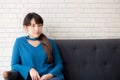 Beautiful portrait young asian woman sitting and smiling happy and looking at camera on sofa with casual at living room Royalty Free Stock Photo