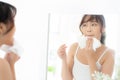 Beautiful portrait young asian woman smiling with skin care cosmetic use oil blotting paper on face looking mirror at room Royalty Free Stock Photo