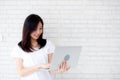 Beautiful of portrait young asian woman smiling and standing holding laptop on brick cement wall background Royalty Free Stock Photo