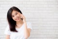 Beautiful of portrait young asian woman talk smart phone and smile standing on cement brick background, freelance female calling Royalty Free Stock Photo