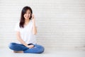 Beautiful of portrait young asian woman talk smart phone and smile sitting on cement concrete brick background Royalty Free Stock Photo