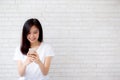 Beautiful of portrait young asian woman touch phone and smile standing on cement brick background Royalty Free Stock Photo