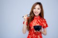 Beautiful portrait young asian woman wear red cheongsam holding chopsticks and bowl isolated on white background Royalty Free Stock Photo