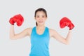 Beautiful portrait young asian woman wearing red boxing gloves flexing with strength and strength isolated Royalty Free Stock Photo