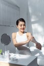 Beautiful portrait young asian woman smile applying sunscreen cream or lotion on skin care at bedroom Royalty Free Stock Photo