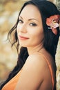 Beautiful portrait of a young brunette woman with orange flower in her hair. Royalty Free Stock Photo