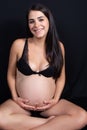 Beautiful Portrait of young pregnant woman underwear sit on black floor background Royalty Free Stock Photo