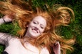 Beautiful portrait of a young sexy red-haired woman, laughing, lying in the spring, summer sun, relaxing on the green meadow grass Royalty Free Stock Photo