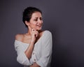Beautiful positive grimacing fun woman with hand under the face thinking and looking up in white shirt on dark purple background Royalty Free Stock Photo