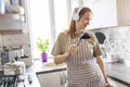 Beautiful positive woman in earphones listening to music and singing into ladle as microphone while cooking in the kitchen. Relax Royalty Free Stock Photo