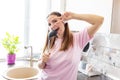 Beautiful positive woman in earphones listening to music and singing into ladle as microphone while cooking in the kitchen. Relax Royalty Free Stock Photo